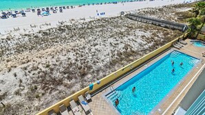 A beach view with a swimming pool, beach umbrellas, and lounge chairs. - Pelican Isle 411 (Fort Walton Beach)
