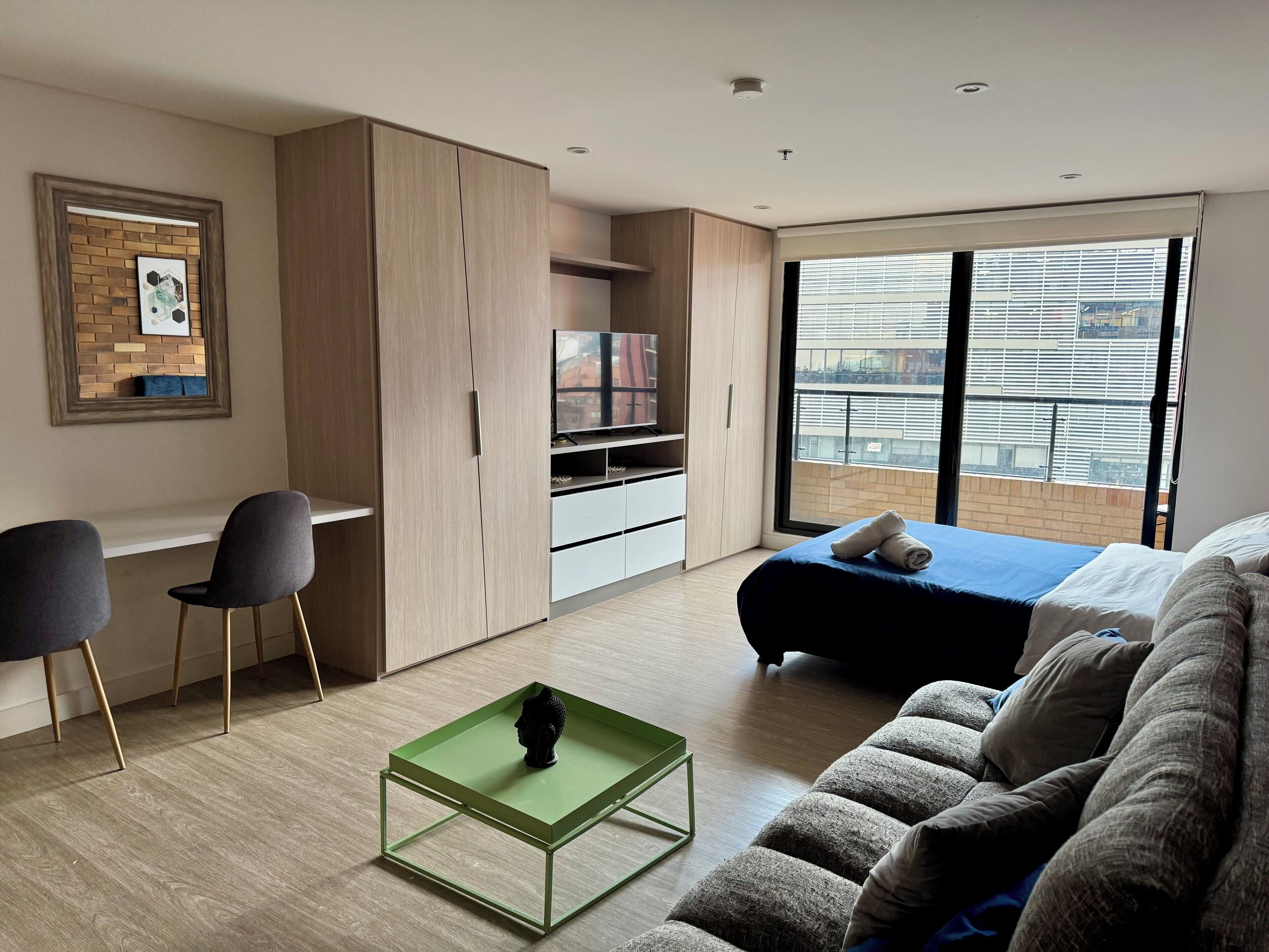 A modern bedroom with a bed, a sofa, a desk, and a TV.