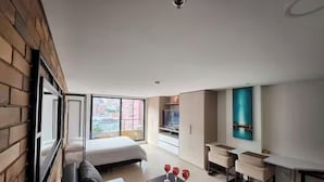 A modern living room with a sofa, a dining table, and a bed.