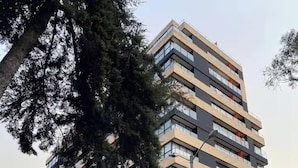 A multi-story building with a modern architectural design, featuring a mix of glass and wooden facade elements.
