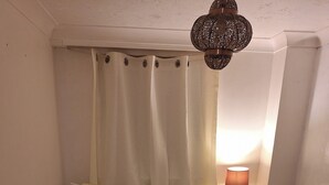 Ein Schlafzimmer mit einem Bett, blumigen Kissen, einer Nachttischlampe und einer Hängelampe.