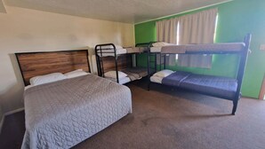 Een kamer met een eenpersoonsbed, twee stapelbedden en een groene wand.