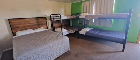 A room with a single bed, two bunk beds, and a green wall.