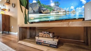 A flat-screen TV mounted on a wooden entertainment center, with a game box labeled "Sorry!" and "Durham Monopoly" visible underneath.