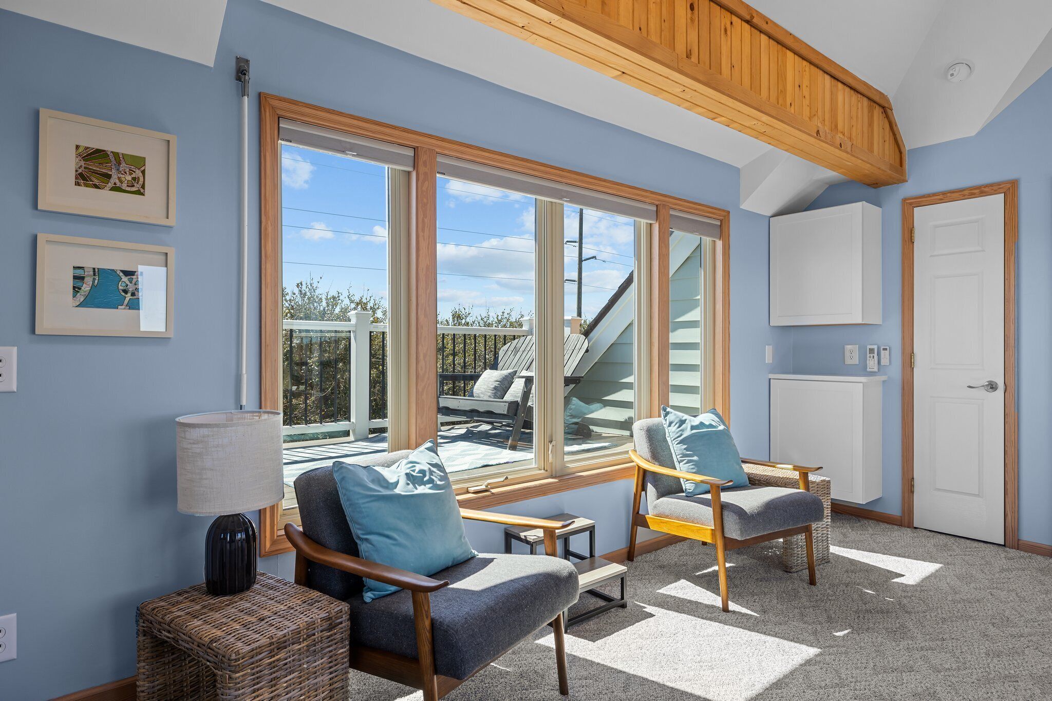 A room with large windows, two chairs, a lamp, and a door.