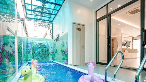An indoor swimming pool with two inflatable rings, a glass ceiling, and a reception area in the background.