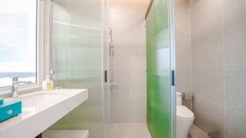 Et moderne badeværelse med en glasbrusekabine, en hvid vask og et toilet.