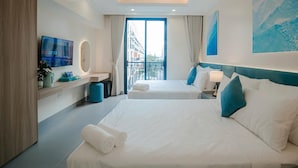 A hotel room with two beds, a TV, a bathroom, and a balcony with a city view.