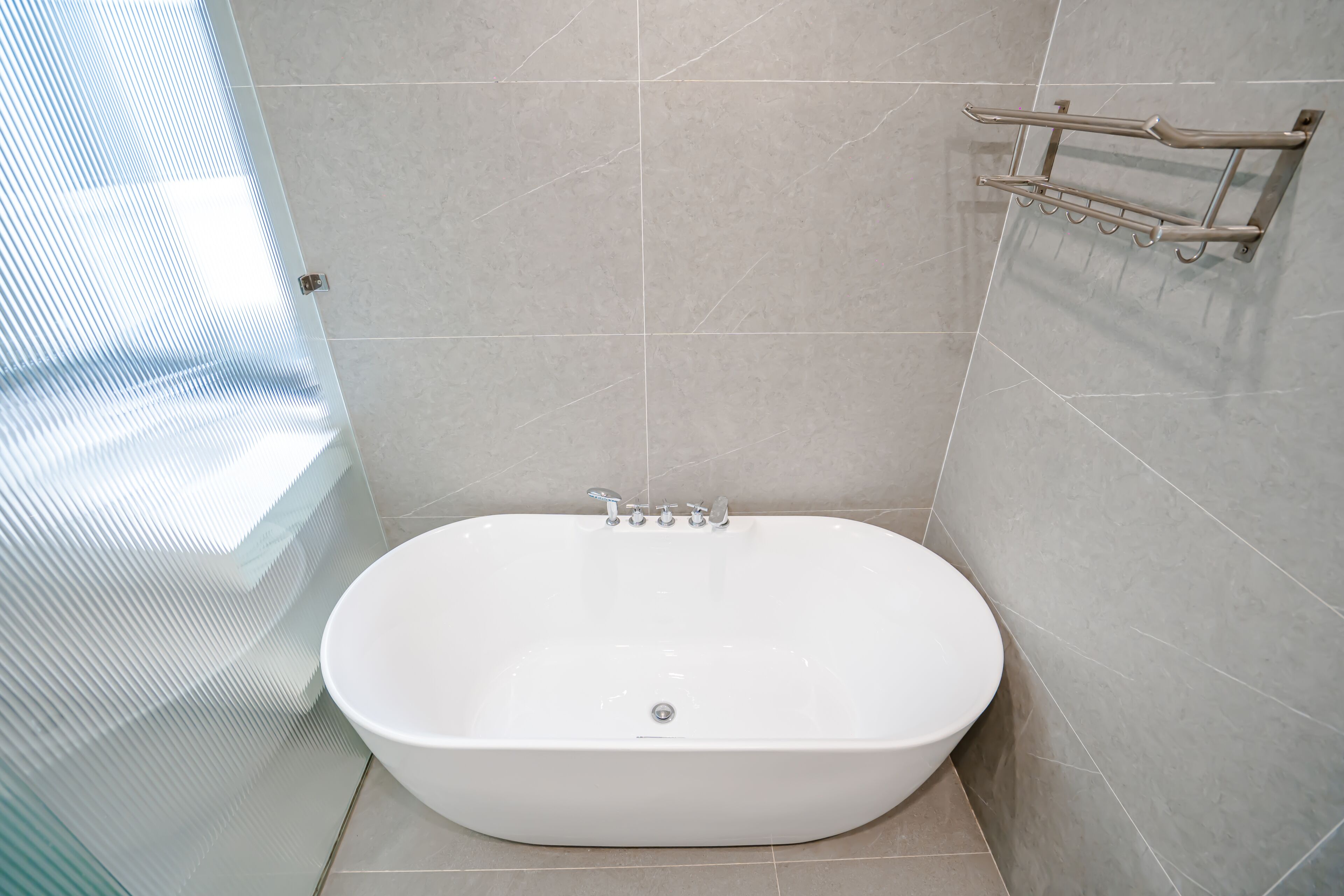 A bathroom with a freestanding bathtub, a glass shower enclosure, and a towel rack.