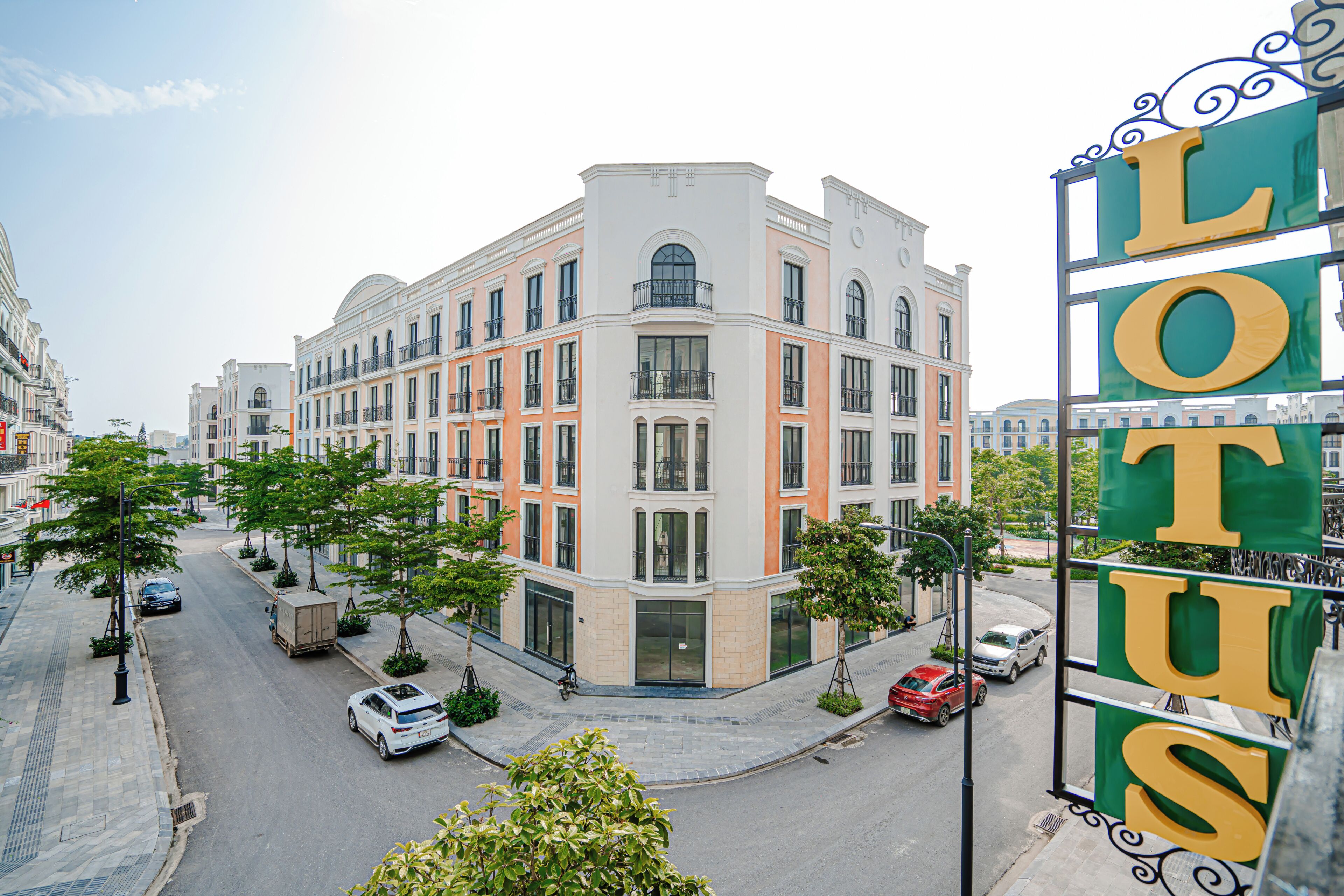 Ein mehrstöckiges Hotel mit auffälliger Schrifttafel, Straßenszene mit Autos und blauem Himmel.