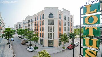 Ein mehrstöckiges Hotel mit auffälliger Schrifttafel, Straßenszene mit Autos und blauem Himmel.