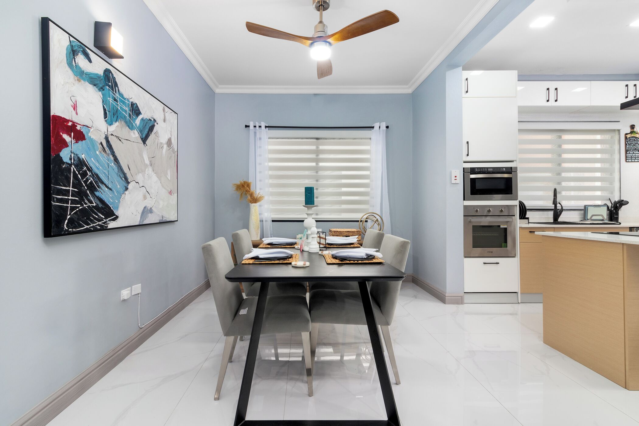 A modern dining area with a black table, white chairs, and a ceiling fan.