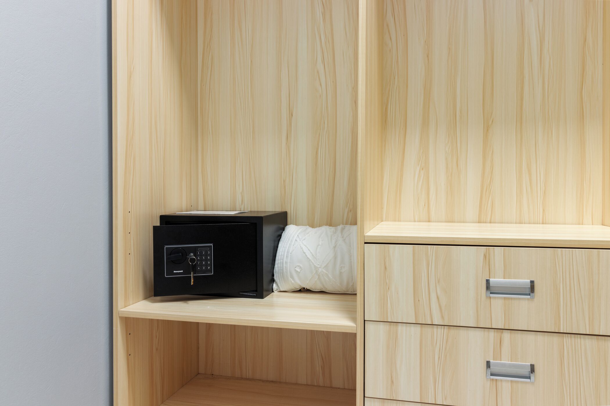 A wooden cabinet with drawers and a black electronic device on a shelf.