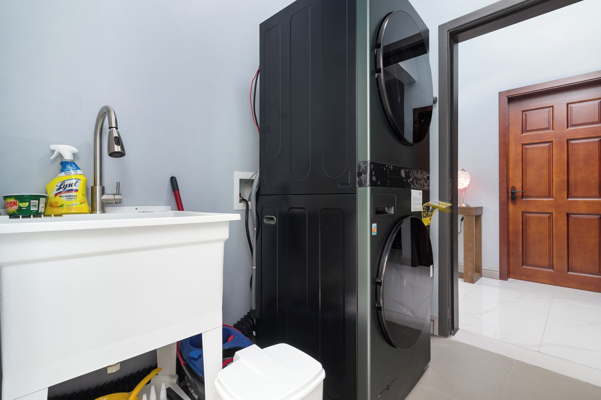 A compact kitchen with a sink, a black refrigerator, and a door leading to another room.