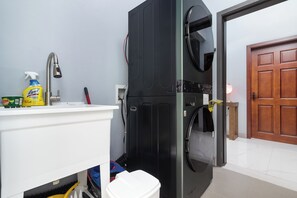 A compact kitchen with a sink, a black refrigerator, and a door leading to another room. - Coastal Escape in Tower Isle BeachNearby (Tower Isle)