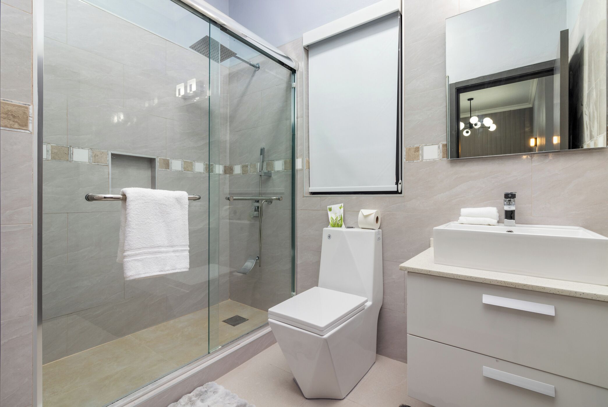 Un bagno moderno con box doccia in vetro, un water e un lavandino con specchio sopra.