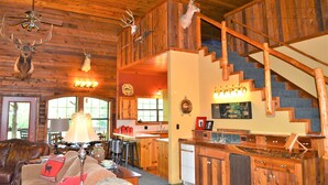 A rustic cabin interior with a wooden staircase, a dining area, and a living room with a fireplace. - Spacious 5-bedroom lodge in Flippin Ar, on the beautiful White River. (Flippin)