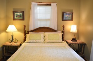 A neatly made bed with floral bedding, two bedside lamps, and two framed pictures on the walls. - Spacious 5-bedroom lodge in Flippin Ar, on the beautiful White River. (Flippin)