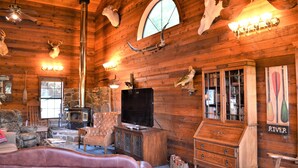 A rustic cabin interior with a fireplace, leather furniture, mounted animal heads, and a television. - Spacious 5-bedroom lodge in Flippin Ar, on the beautiful White River. (Flippin)