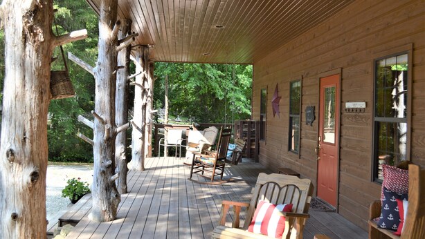 A wooden cabin with a porch, rocking chairs, and a red door. - Spacious 5-bedroom lodge in Flippin Ar, on the beautiful White River. (Flippin)