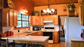 A kitchen with wooden cabinets, a stove, a microwave, and a refrigerator. - Spacious 5-bedroom lodge in Flippin Ar, on the beautiful White River. (Flippin)