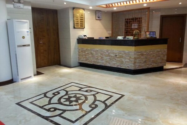 A reception area with a marble floor, a reception desk, a wooden door, and a wall-mounted clock. - Yanrui Hotel (Shanghai)