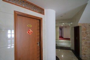 Un couloir d’hôtel avec une porte en bois, un pilier blanc et un mur en pierre.