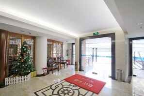 A hotel lobby with a Christmas tree, a reception desk, and a red carpet.