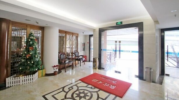 A lobby with a Christmas tree, a red carpet, and a staircase leading to an upper floor.
