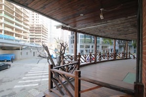 An outdoor wooden deck with a railing, surrounded by buildings. - Yanrui Hotel (Shanghai)