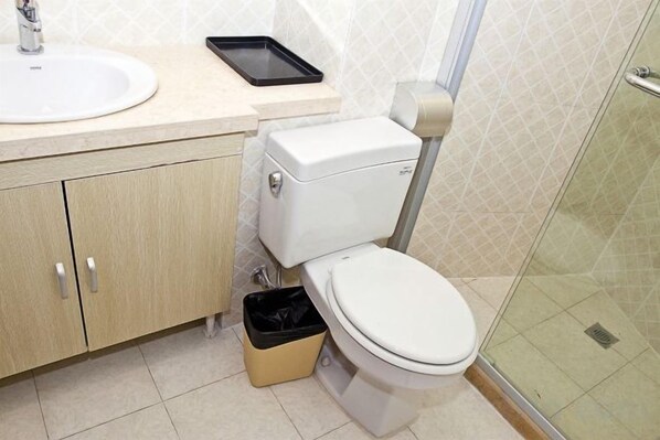 A bathroom with a toilet, sink, and shower.