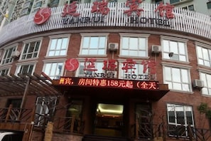 A hotel with a curved facade, multiple windows, and a sign indicating a room rate. - Yanrui Hotel (Shanghai)