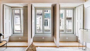 A room with three large windows, a wooden ceiling, and a bed with a pillow.