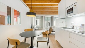 A modern kitchen with white cabinets, a black dining table, and wooden chairs.