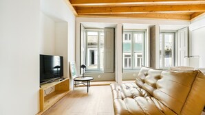 A modern living room with a leather sofa, a TV, and a small table.