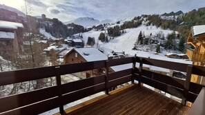 A wooden balcony overlooking a snowy mountain village with traditional buildings.