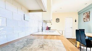 A modern kitchen with white cabinets, a marble countertop, and a wooden dining table with chairs. - Beautiful, fully equipped, pet friendly 3 bedroom house in Shakespeare County. (Alcester)