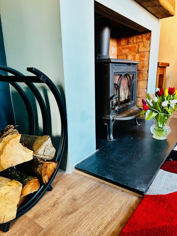 A living room with a fireplace, a wooden bench, and a vase of tulips. - Beautiful, fully equipped, pet friendly 3 bedroom house in Shakespeare County. (Alcester)