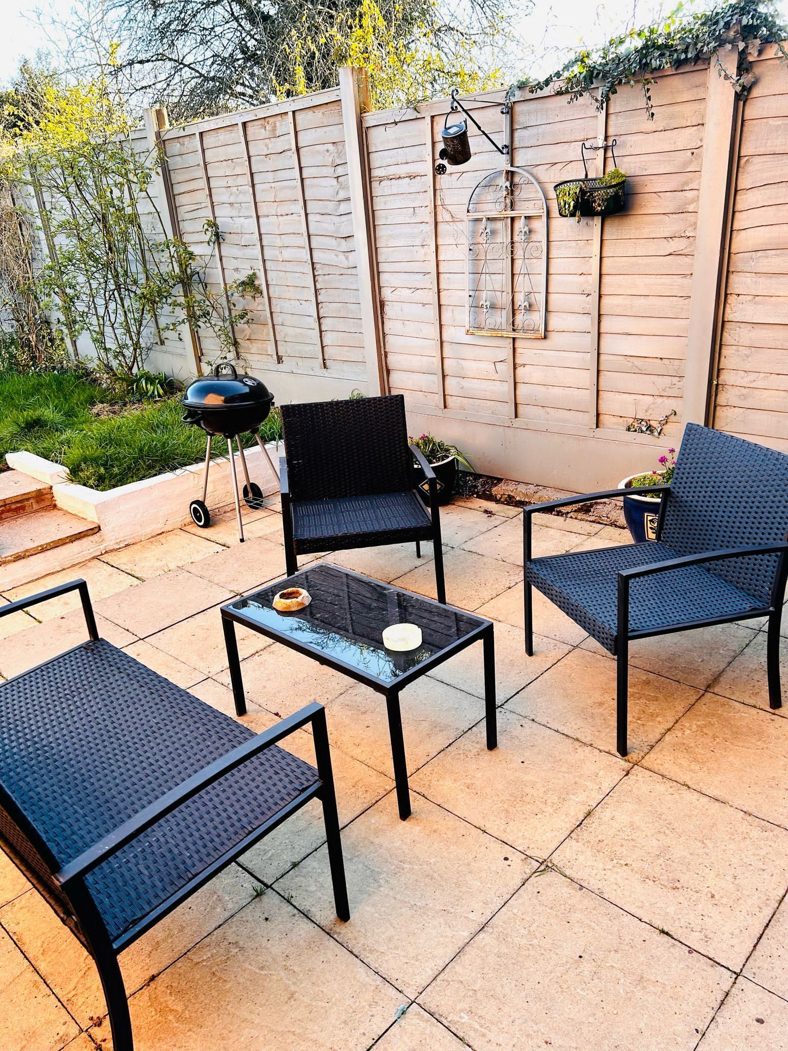 Une terrasse extérieure équipée d’un barbecue, de deux chaises et d’une table.