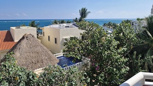 A rooftop pool area with a thatched roof, surrounded by lush greenery and overlooking a coastal view. - Very spacious and incredible views (Puerto Morelos)