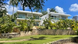 A modern two-story house with a stone wall and lush greenery. - A luxurious and peaceful place with AC, free WIFI, private patio, and balcony! (Sosúa)