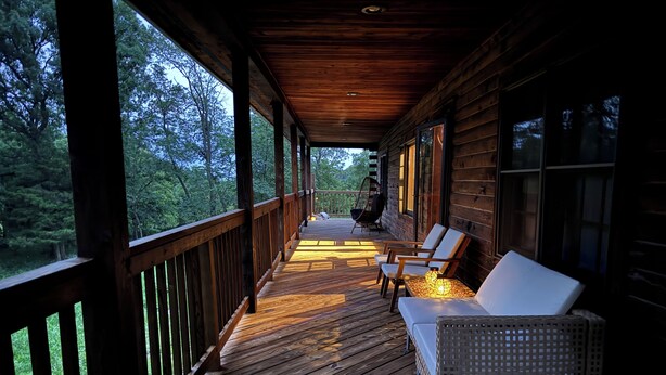 A wooden deck with a sofa and chairs, overlooking a forested area. - Beautiful Log House  4 Bed, 2 Baths, 15 acre land, close to Madison, sleeps 13 (Albany)