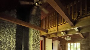 A cozy cabin interior with a stone wall, a wooden ceiling, a sofa, and a fireplace. - Beautiful Log House  4 Bed, 2 Baths, 15 acre land, close to Madison, sleeps 13 (Albany)