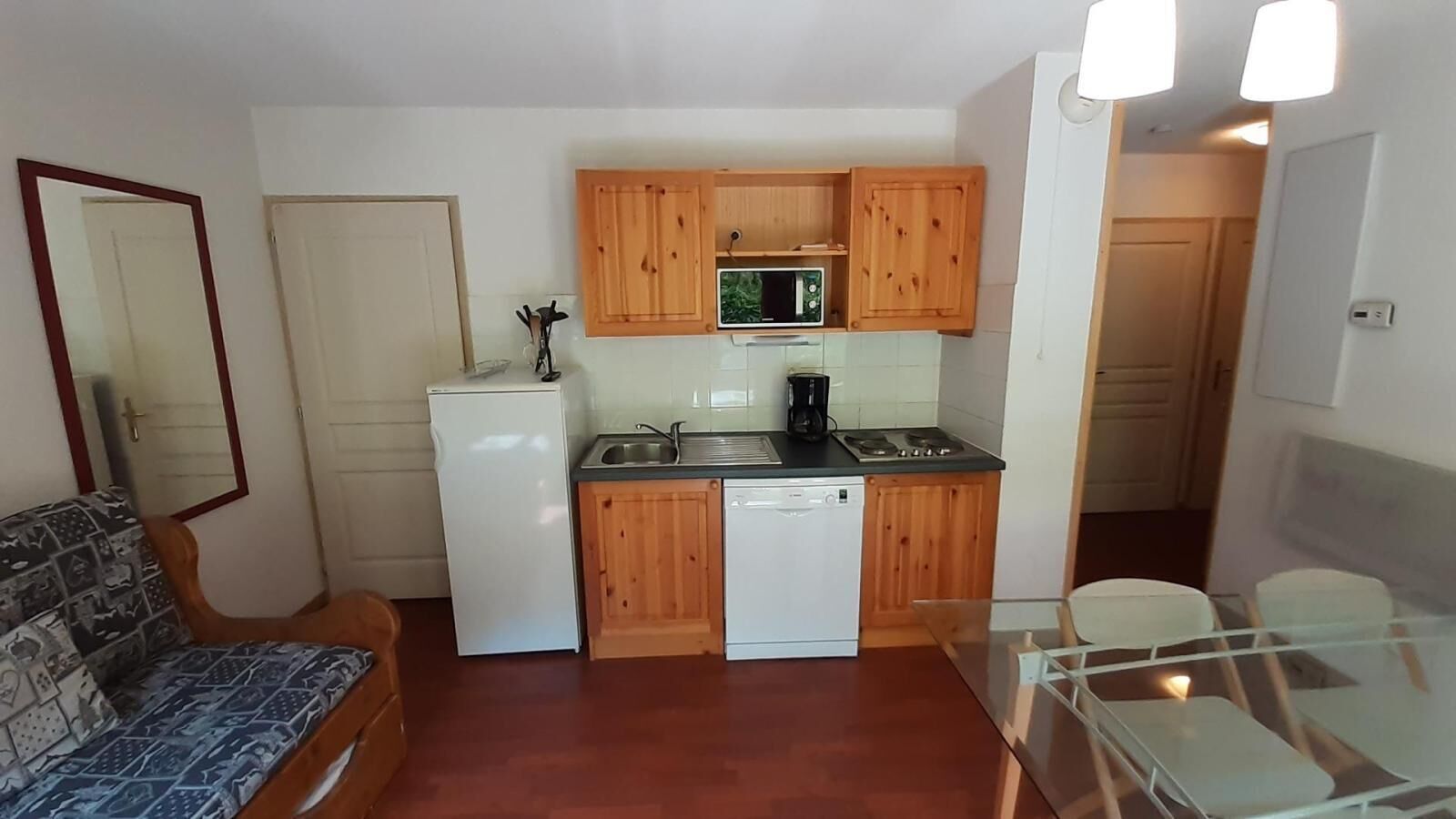 A compact kitchen with wooden cabinets, a refrigerator, a microwave, and a dishwasher.