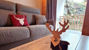 A living room with a grey sofa, a wooden coffee table with a decorative deer head, and a balcony with a railing. - 200m from ski slopes, floor -1, terrace, tv, ski locker, 45m², Valfréjus (Valfréjus)