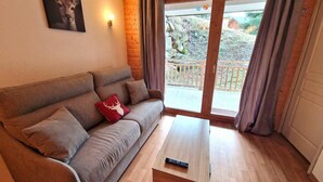 A living room with a sofa, a coffee table, and a balcony with curtains. - 200m from ski slopes, floor -1, terrace, tv, ski locker, 45m², Valfréjus (Valfréjus)