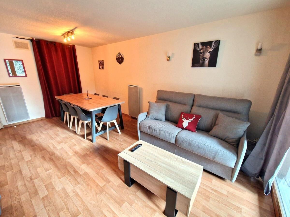 A living room with a sofa, a coffee table, a dining table with chairs, and a red curtain.