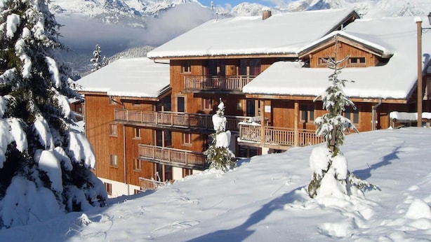 A wooden chalet with multiple balconies, surrounded by snow-covered trees and mountains in the background. - 200m from ski slopes, floor -1, terrace, tv, ski locker, 45m², Valfréjus (Valfréjus)