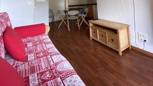 A living room with a sofa, a wooden cabinet, and a television mounted on the wall.
