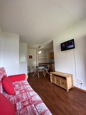 Uma sala de estar com sofá, um armário de madeira e uma televisão na parede.